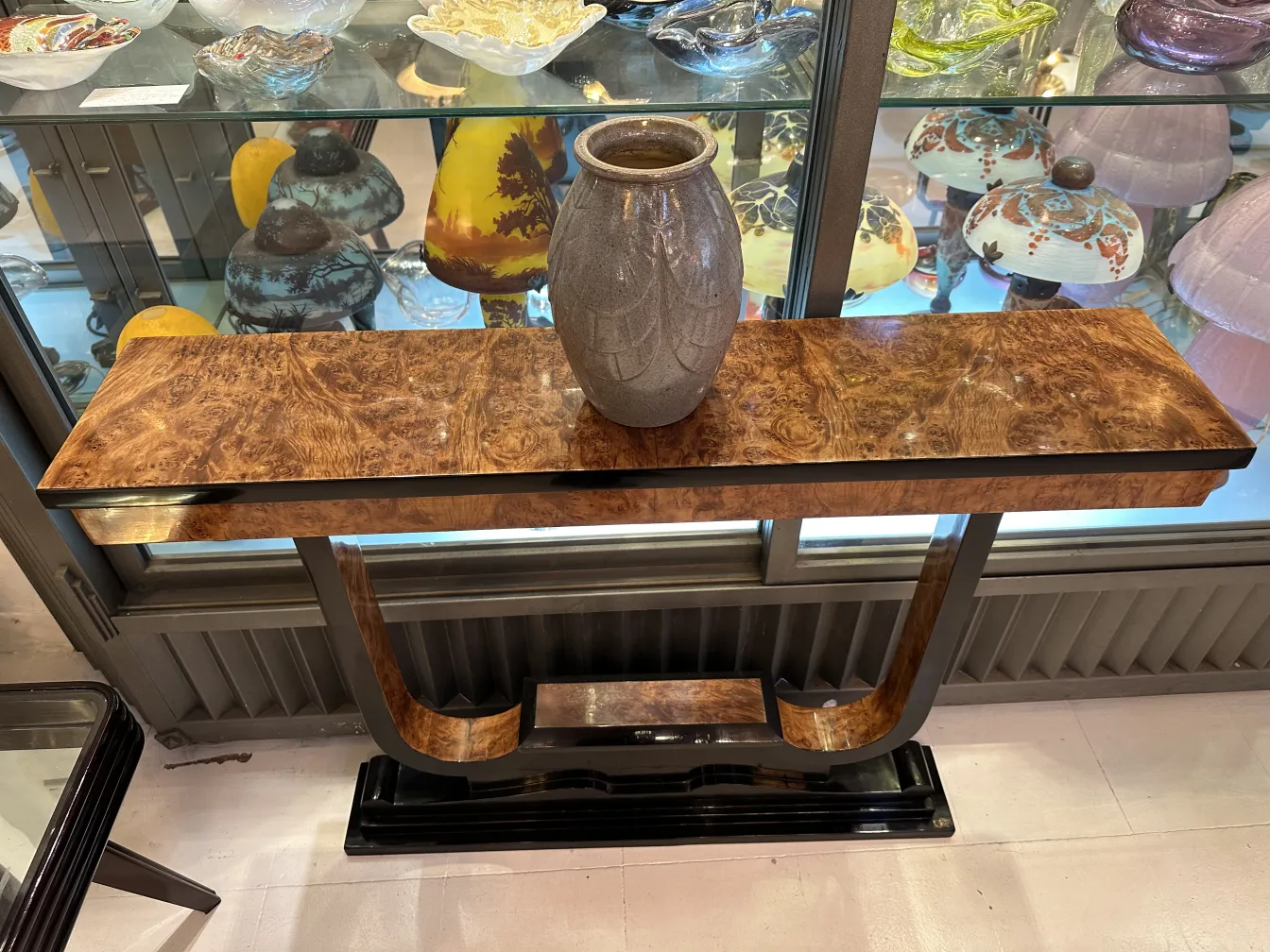 Jarrón de cerámica antigua sobre mesa de madera decorativa.