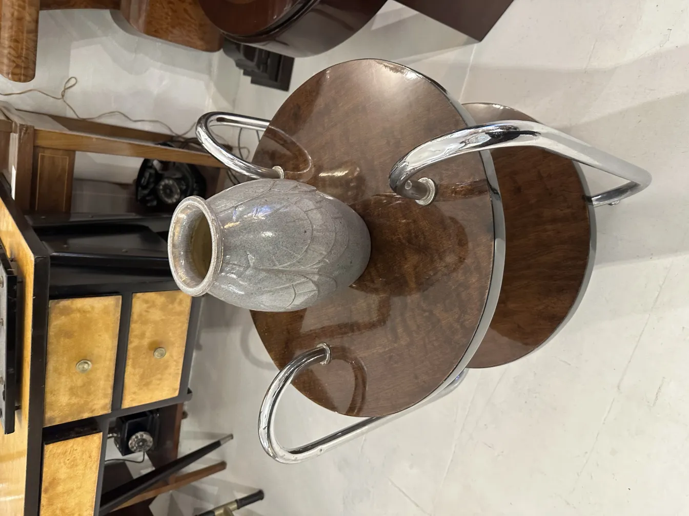 Vaso de cerâmica antiga com acabamento cinza e padrão em uma mesa de madeira.