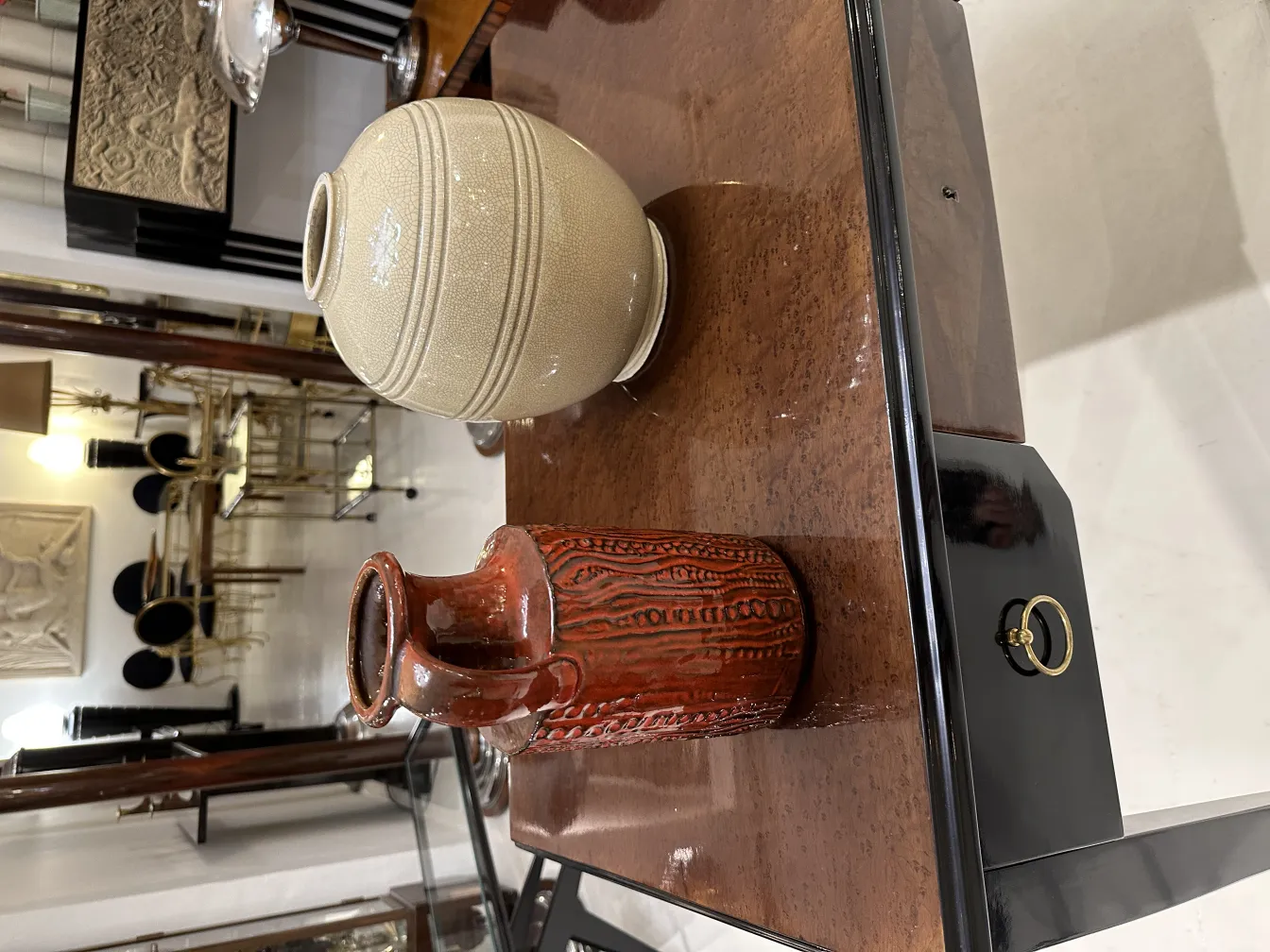 Jarra de cerámica antigua con trama en relieve sobre una mesa de madera brillante.