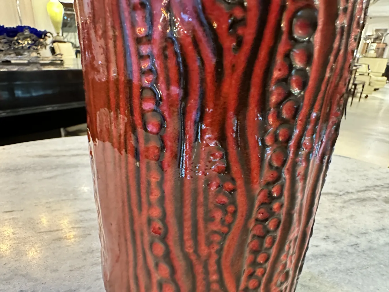 Antiga cerâmica com textura em tons de vermelho e preto, apresentando designs únicos em um ambiente de antiguidades.
