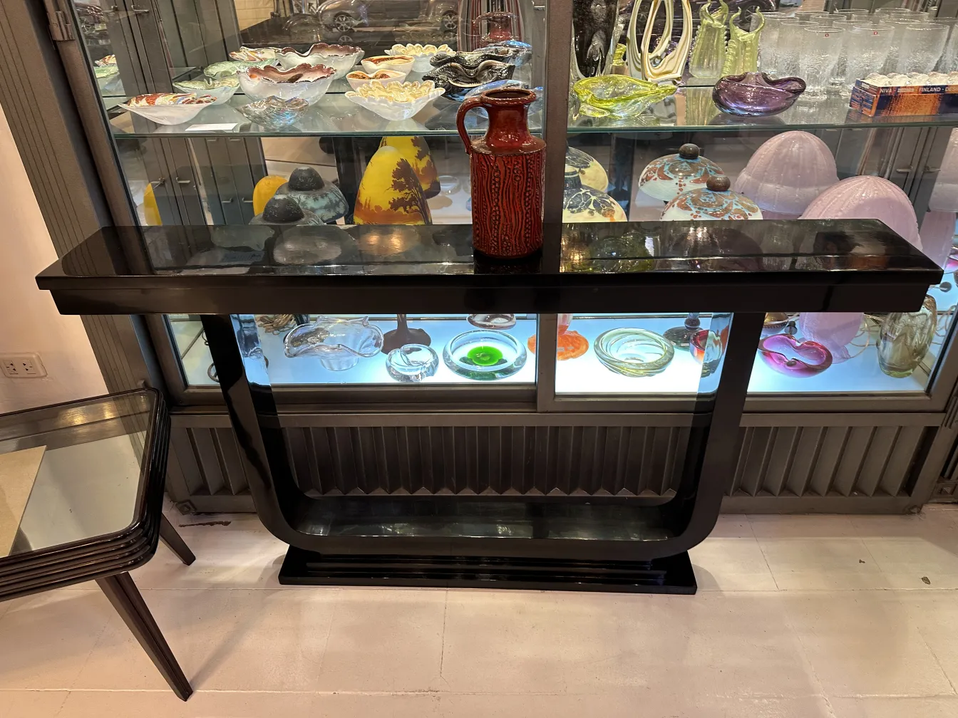 पुरानी मिट्टी के पात्र का फूलदान, काले मेज पर रंगीन डिज़ाइन के साथ, सजावटी वस्तुओं से घिरा हुआ।