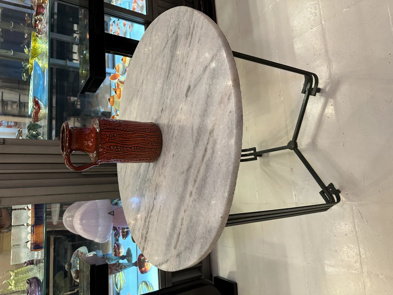 Antique decorative red ceramic jug on marble table.