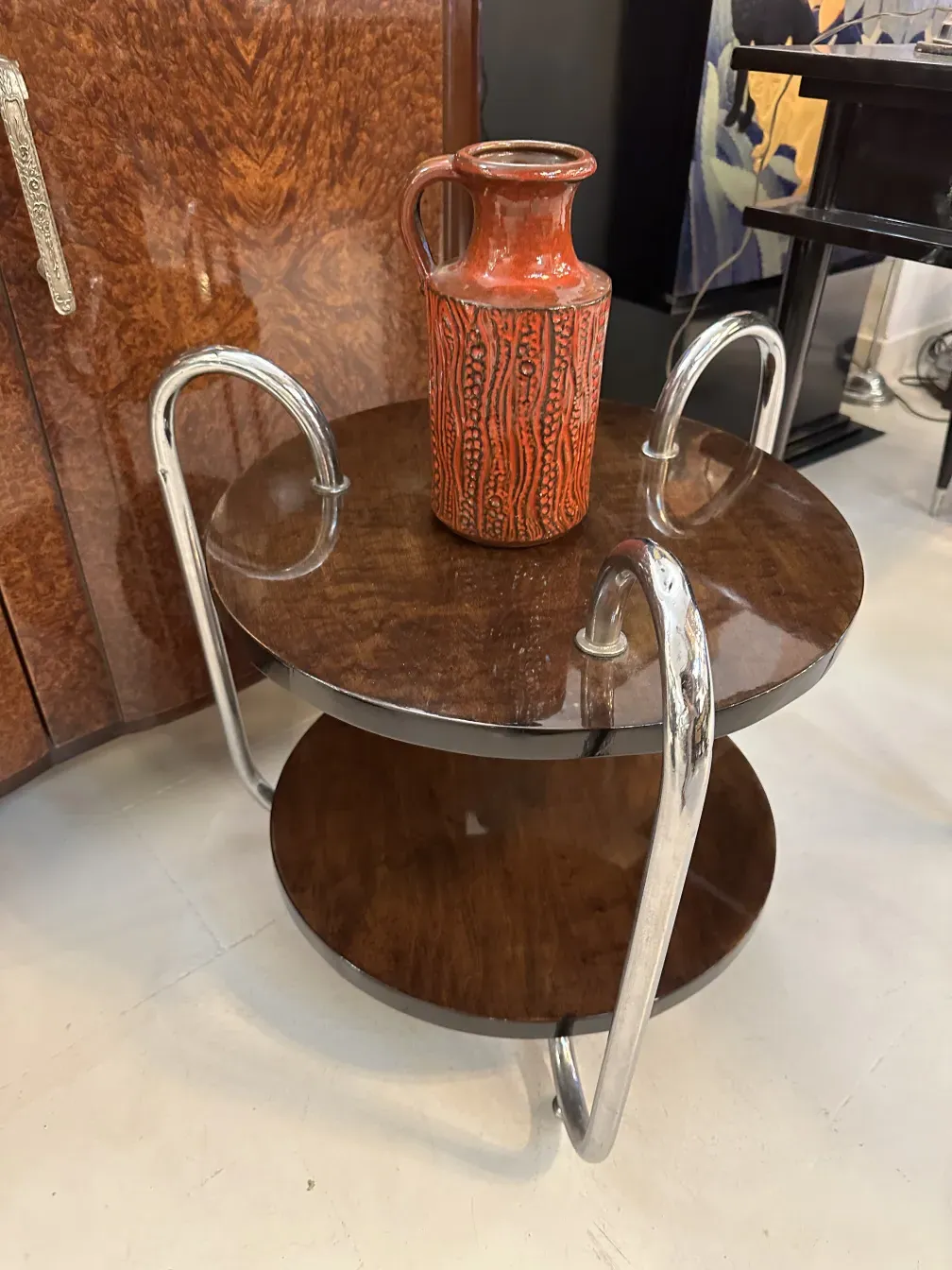 Jarrón antiguo de cerámica con diseño texturizado en tonos rojos, sobre mesa decorativa.