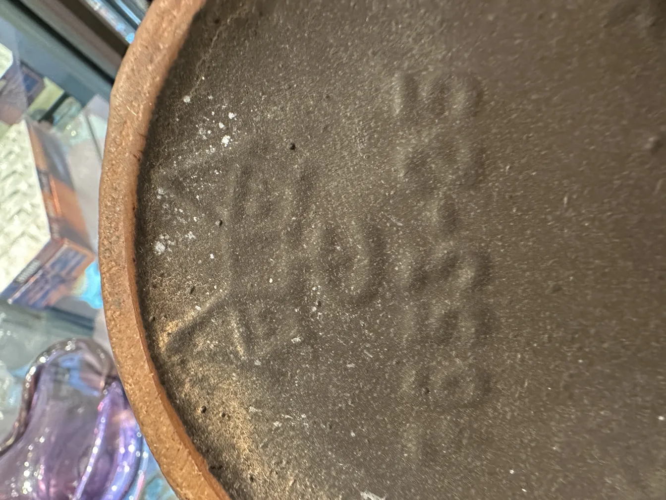 Base di ceramica antica con iscrizioni visibili.