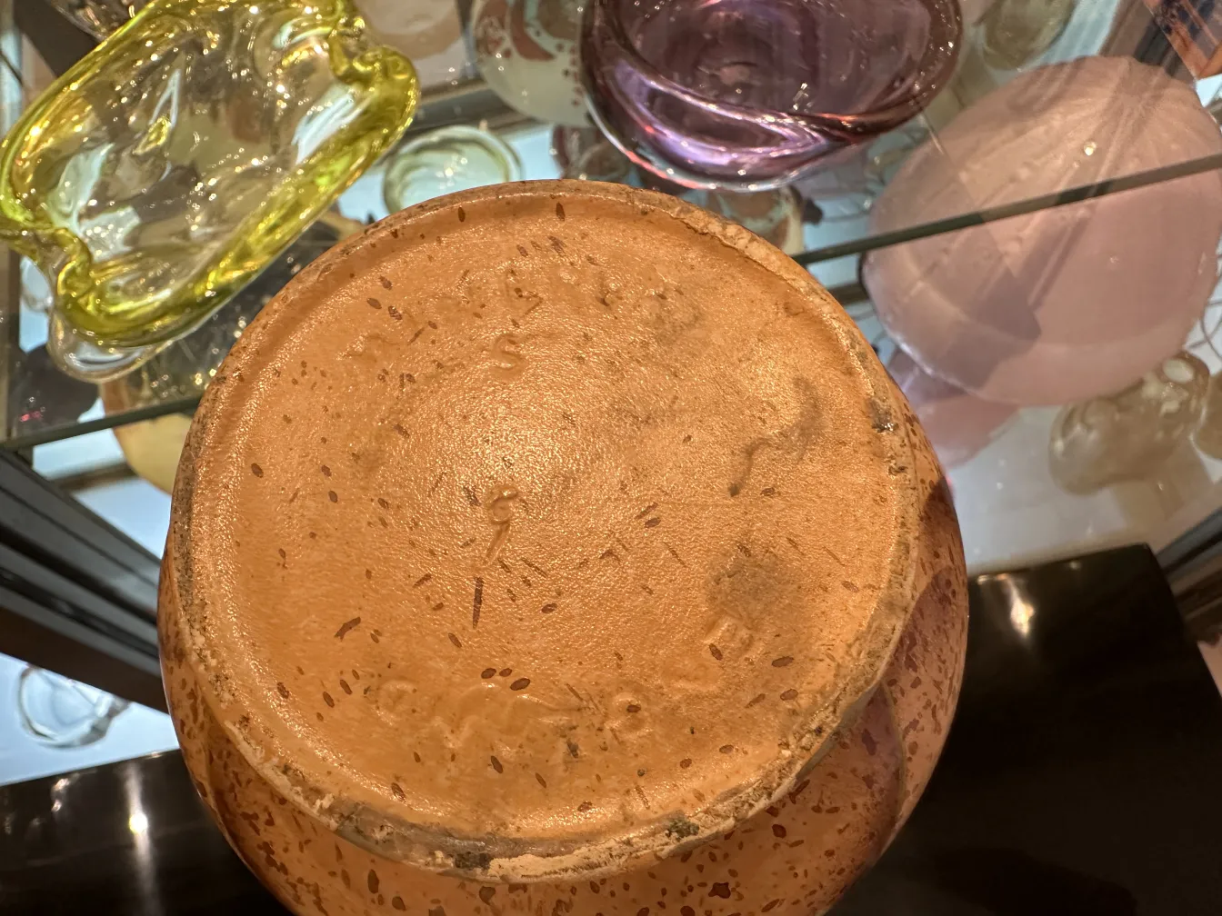 Base di ceramica antica con dettagli unici. Sfondo di altri oggetti decorativi.