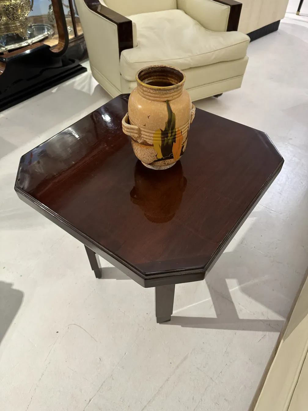Vaso de cerâmica antiga sobre uma mesa octogonal em um ambiente elegante.