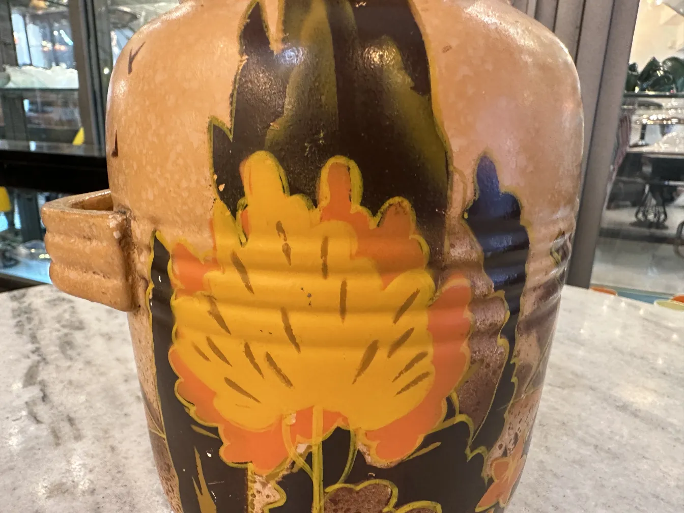 黄色とオレンジの花で飾られた古い陶器の壺。