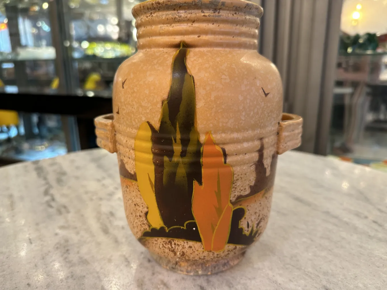 Antique ceramic vase with a painted landscape in warm colors.