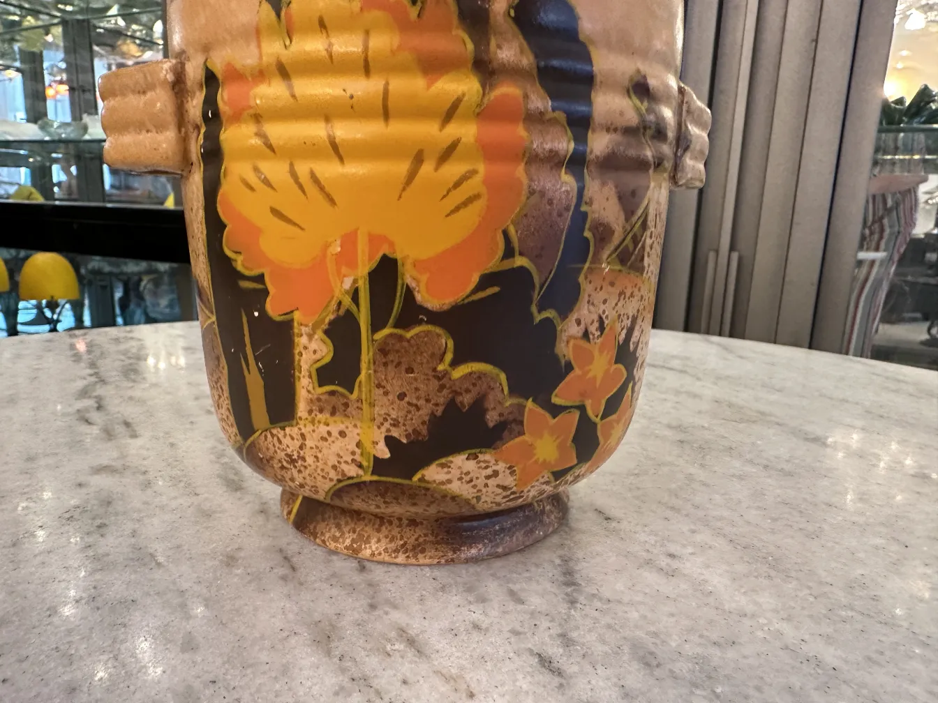 Vase en céramique ancienne avec décoration florale colorée sur fond sombre.