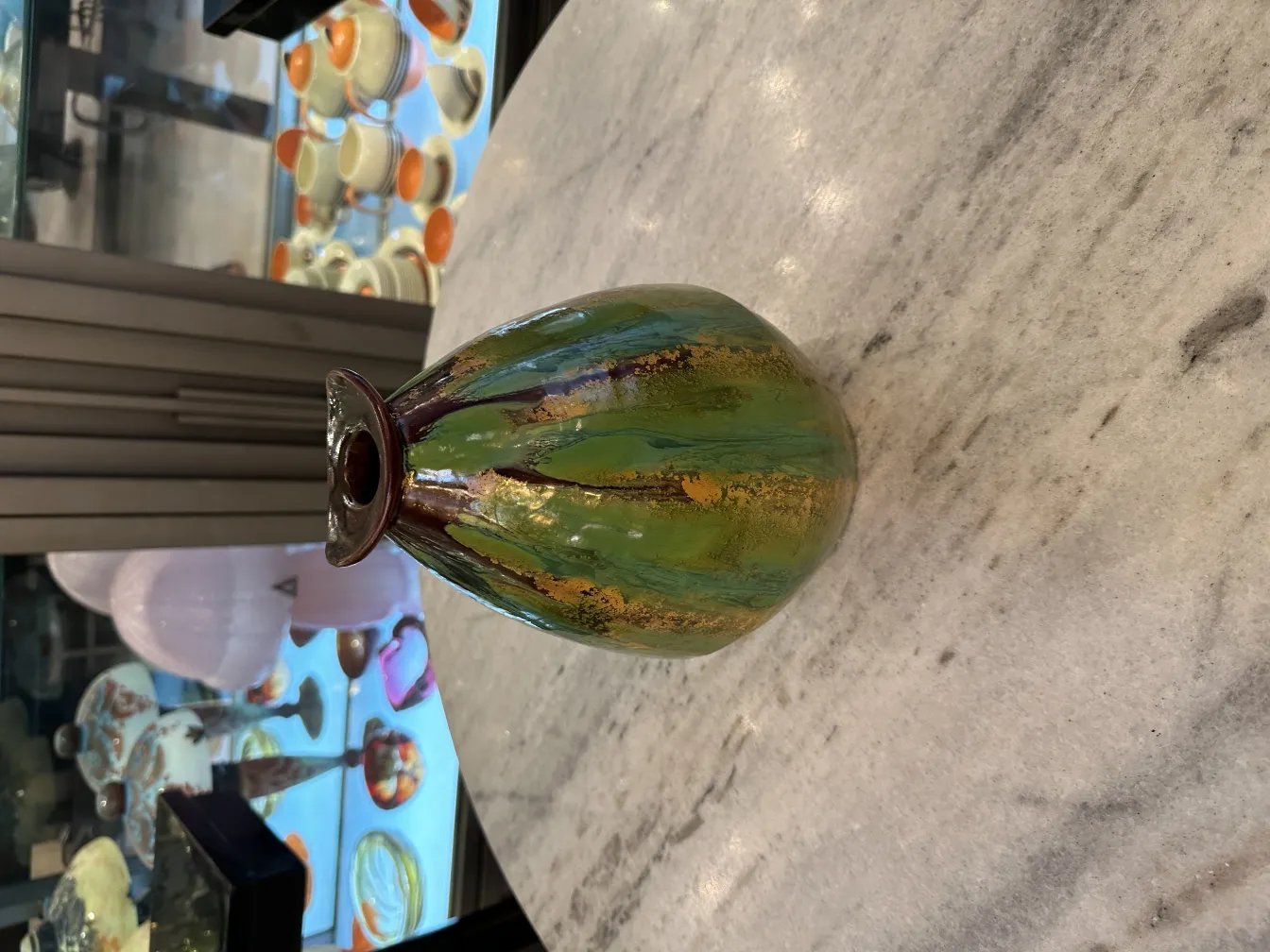 Vaso de cerâmica antiga em verde e dourado, fundo decorativo.