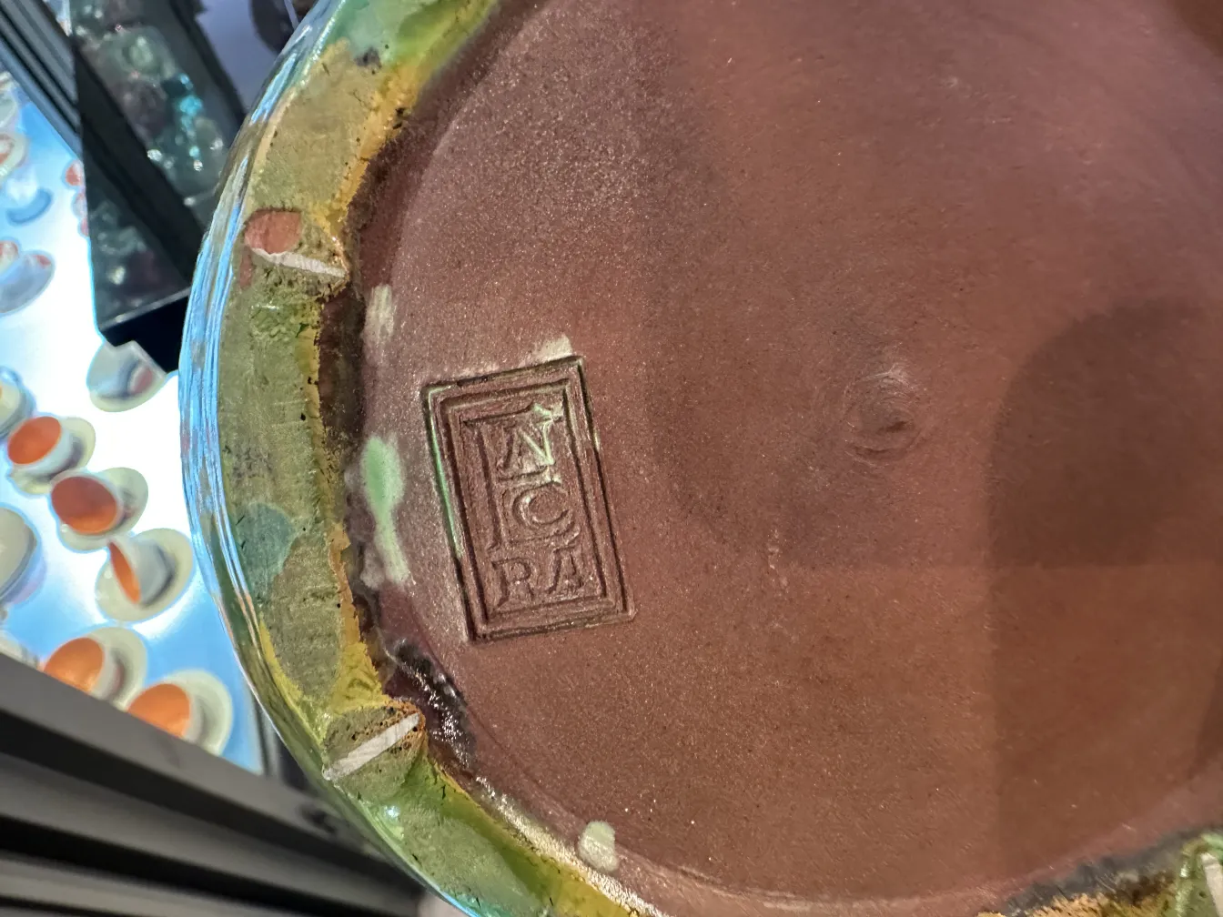 Tazza in ceramica antica con decorazioni colorate e un sigillo sul fondo.