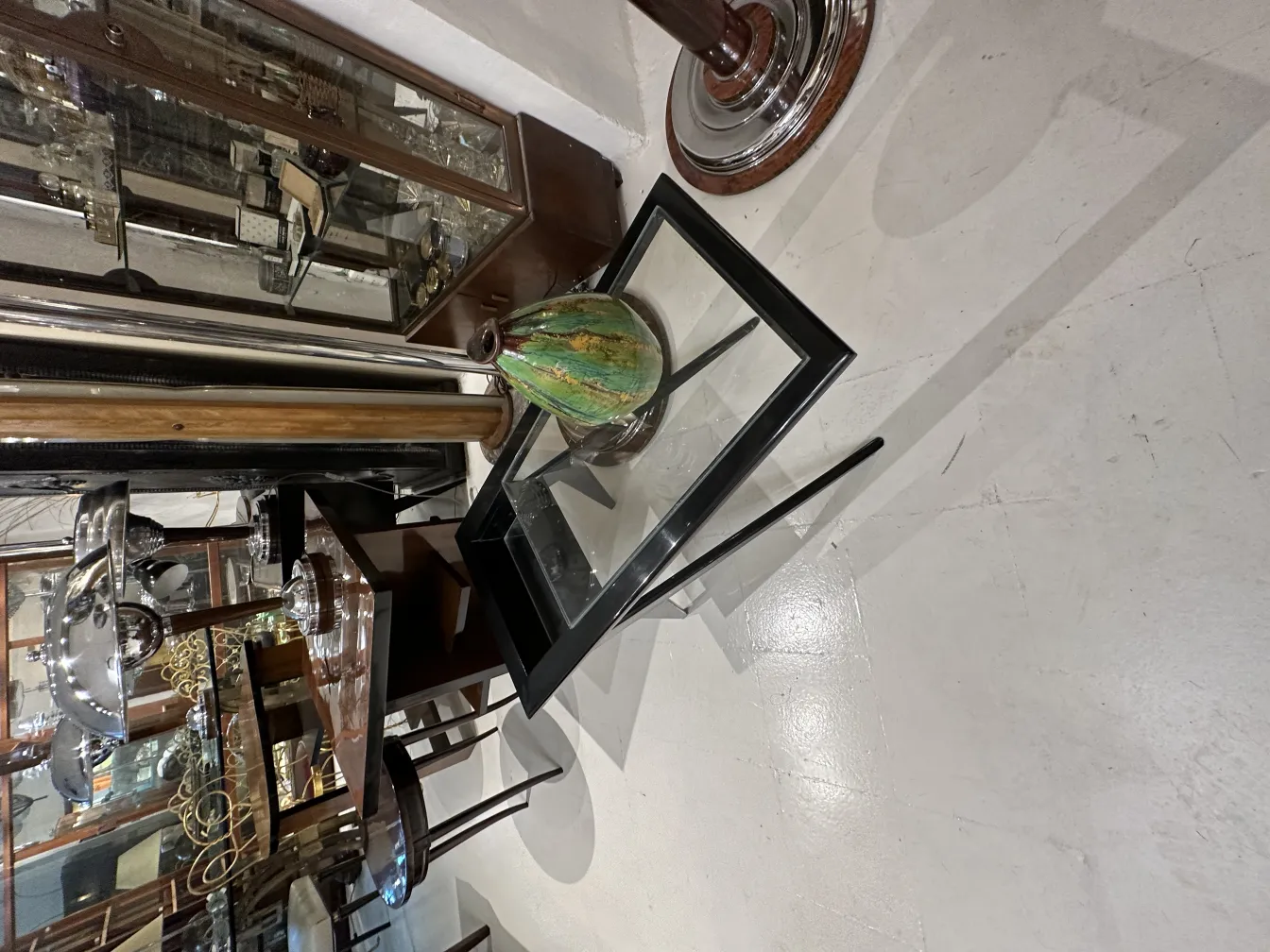 Vaso de cerâmica antiga com detalhes em verde, cercado por antiguidades