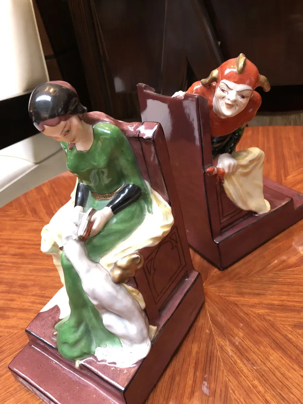 Escultura de cerâmica antiga representando um personagem curioso e um pensativo, ambientados em um ambiente elegante.