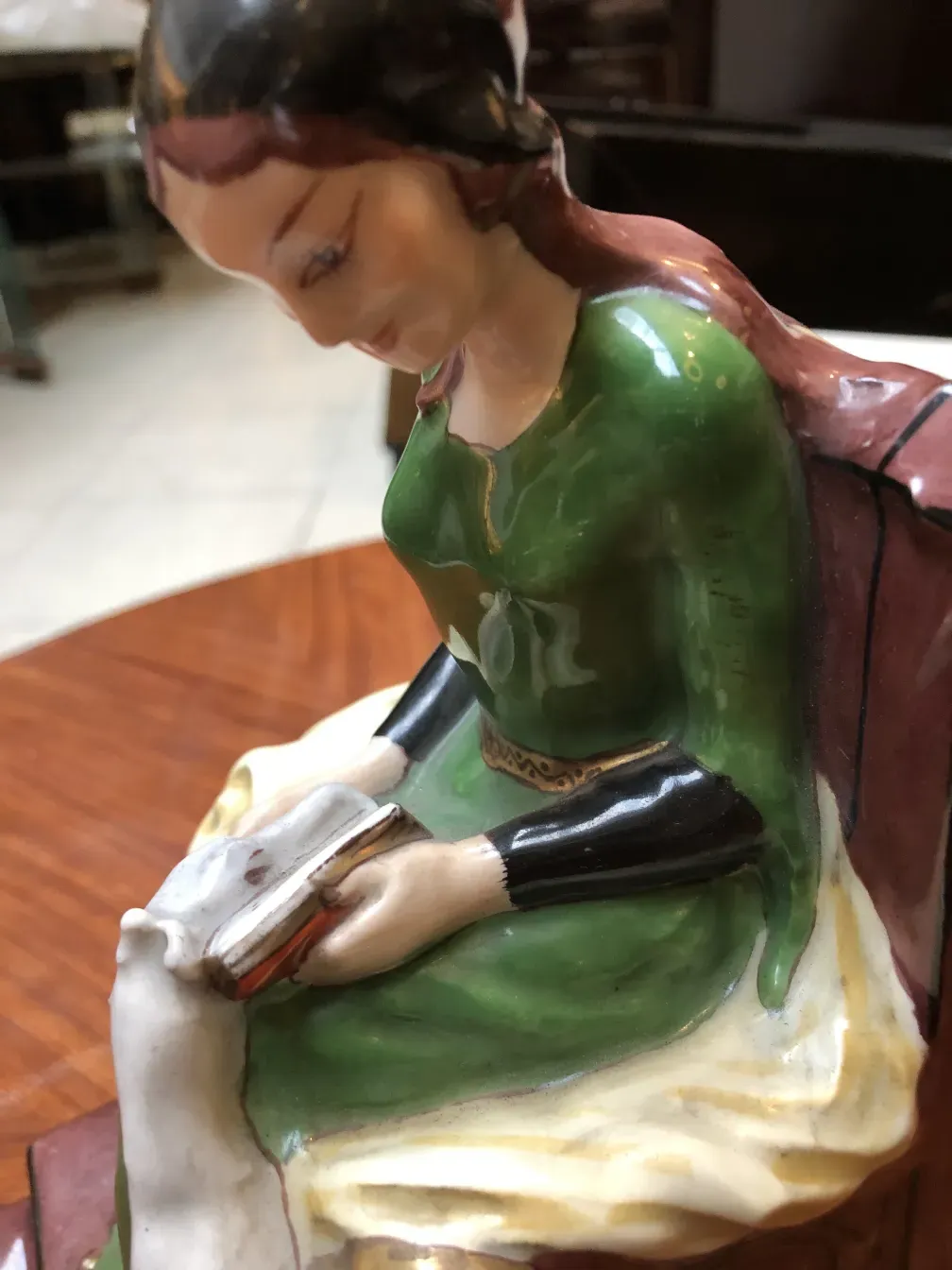 Figura de cerâmica antiga de uma mulher lendo em um ambiente aconchegante.