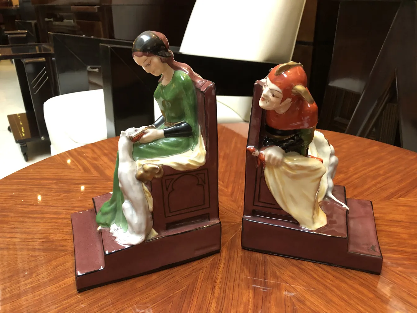 Antique ceramic sculptures of two characters in an elegant setting.