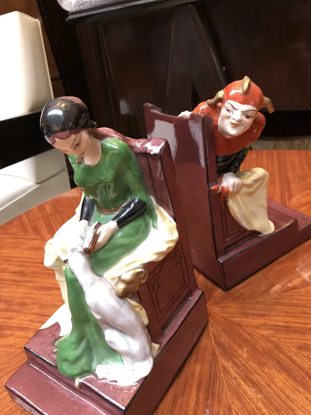 Figura de cerâmica antiga com personagens pintados, ambiente elegante.