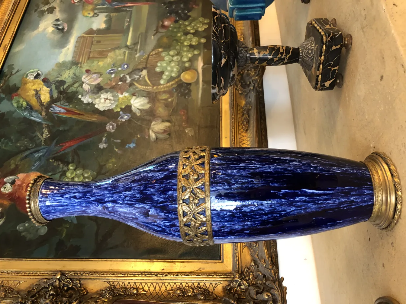 Vase en céramique bleue avec détails dorés, dans un cadre ancien.