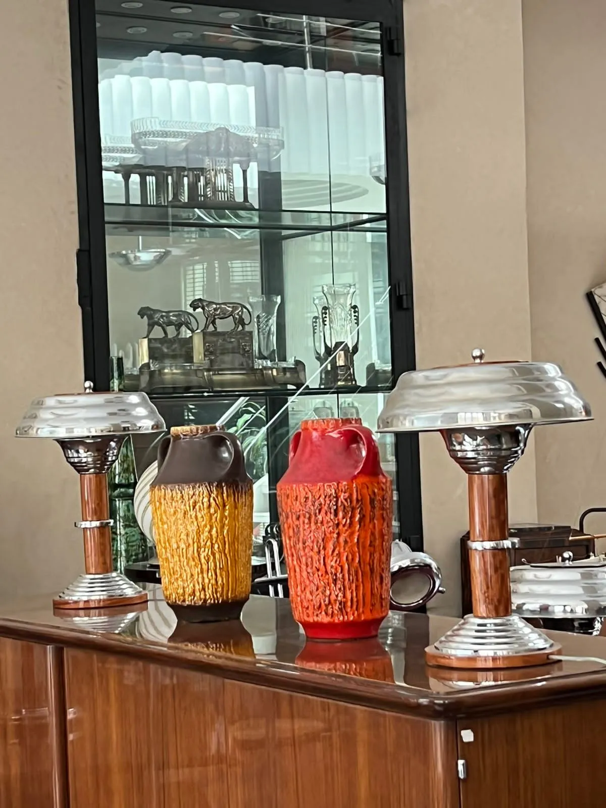 Trois vases en céramique ancienne de teintes chaudes sur une table. Étagère en verre en arrière-plan.