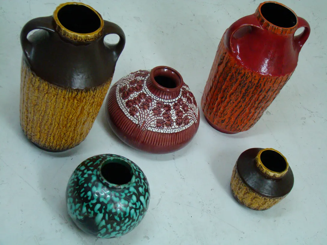 Vasos de cerámica antigua de diferentes colores y formas en un fondo blanco