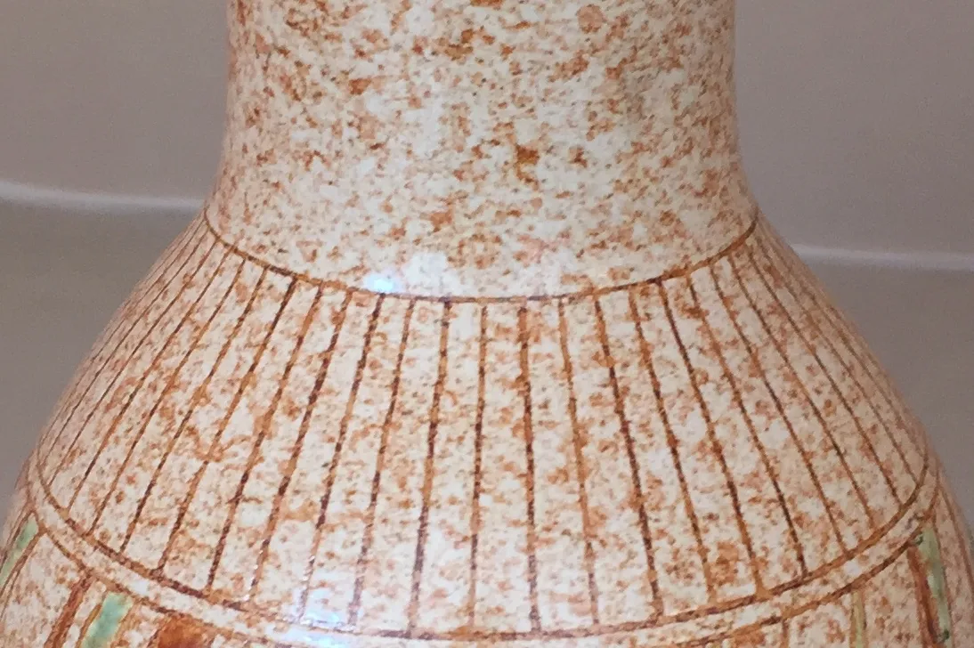 Vaso de cerâmica antiga com design listrado e cores suaves.