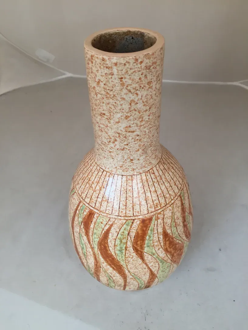 Ancien objet en céramique avec des dessins colorés sur le corps.