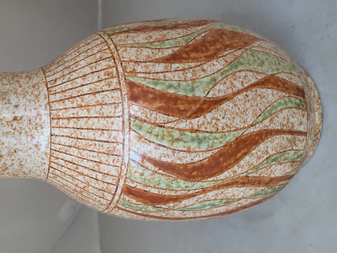 古代の波状デザインの陶器花瓶は、茶色と緑のトーンで彩られています。