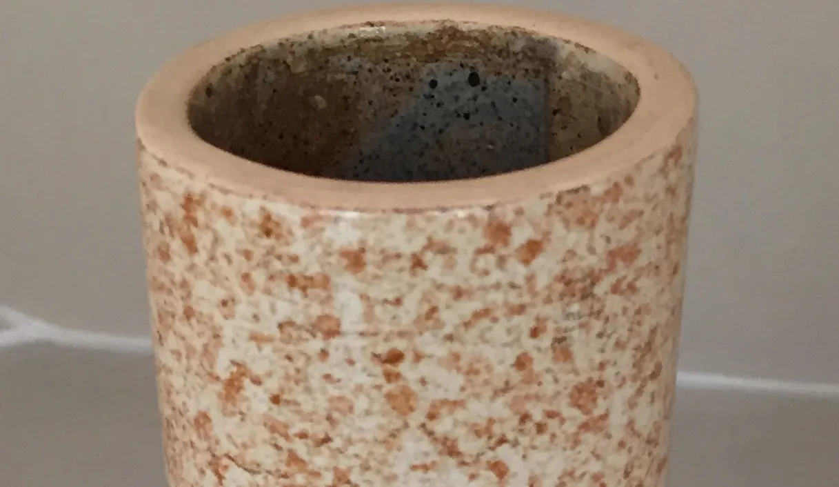 Vaso de ceramica antiga com textura irregular e tons naturais.