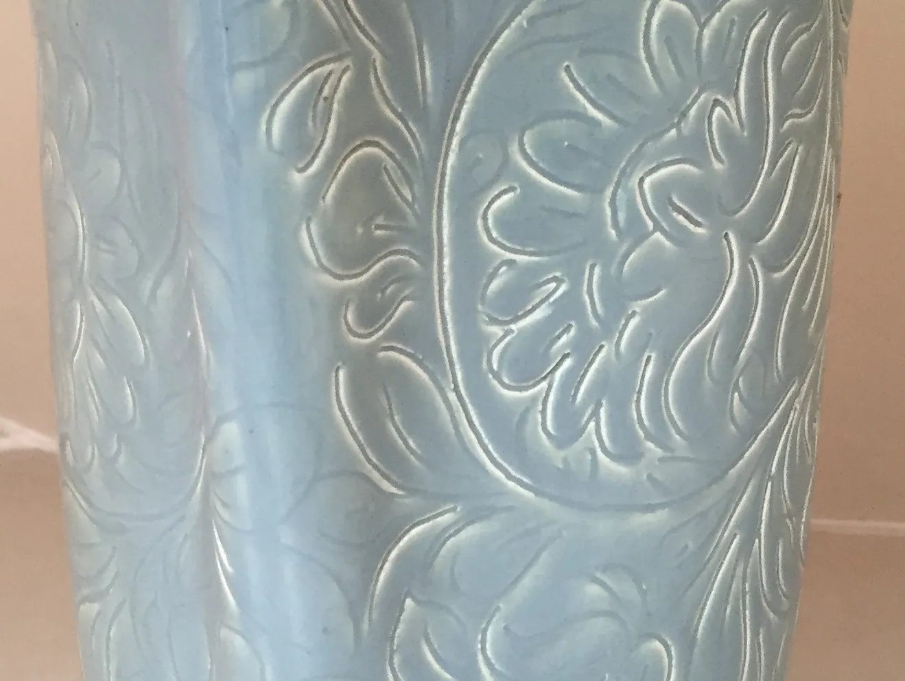 Vase en céramique ancienne avec un design en relief complexe, couleur bleu clair.