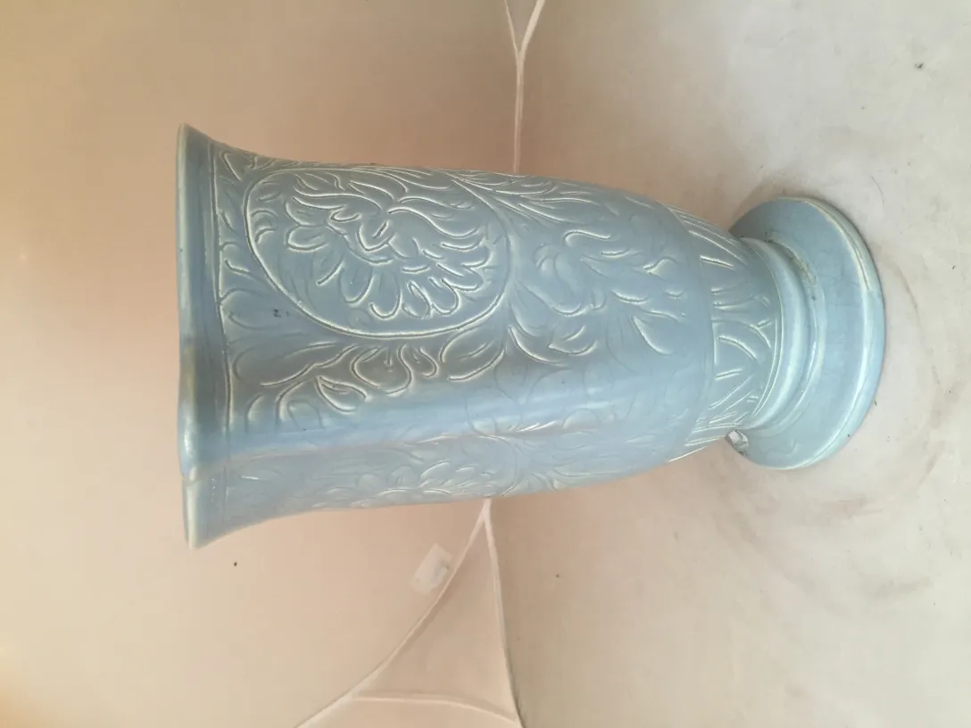 Vase en céramique antique avec des reliefs décoratifs en tons bleus.