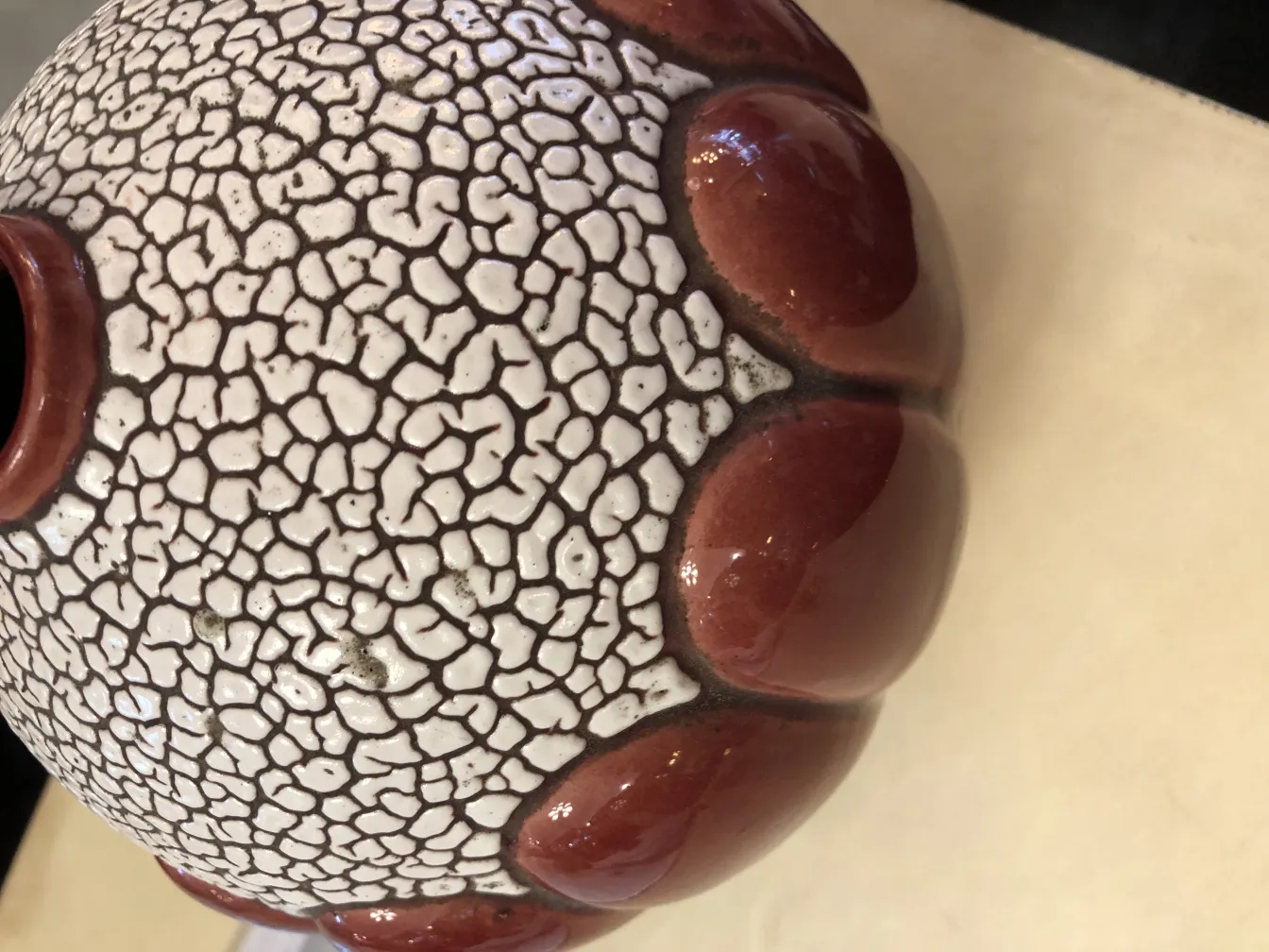 Vaso in ceramica antica con texture crepata e dettagli rossi.