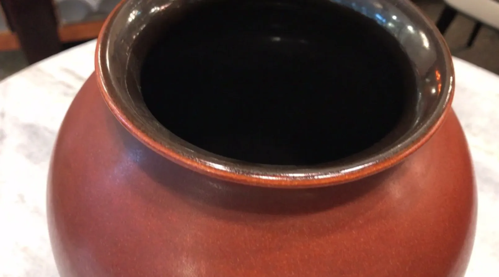 Jarre de cerámica antigua de Scheurich, de color marrón con un borde negro, fondo oscuro.
