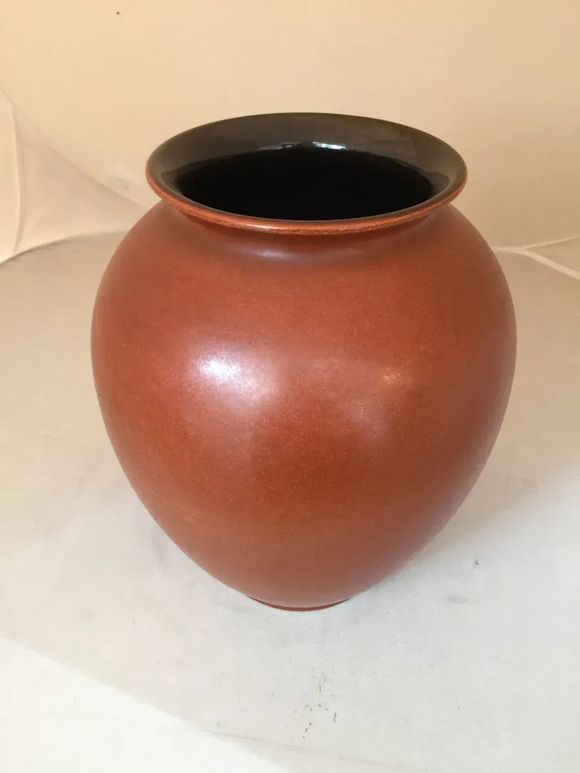 古い陶器の球、赤土色と黒い縁、シンプルな環境。