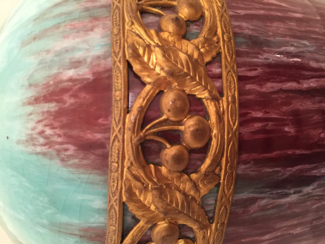 Antique ceramic with intricate golden ornamentation on a multicolored background.