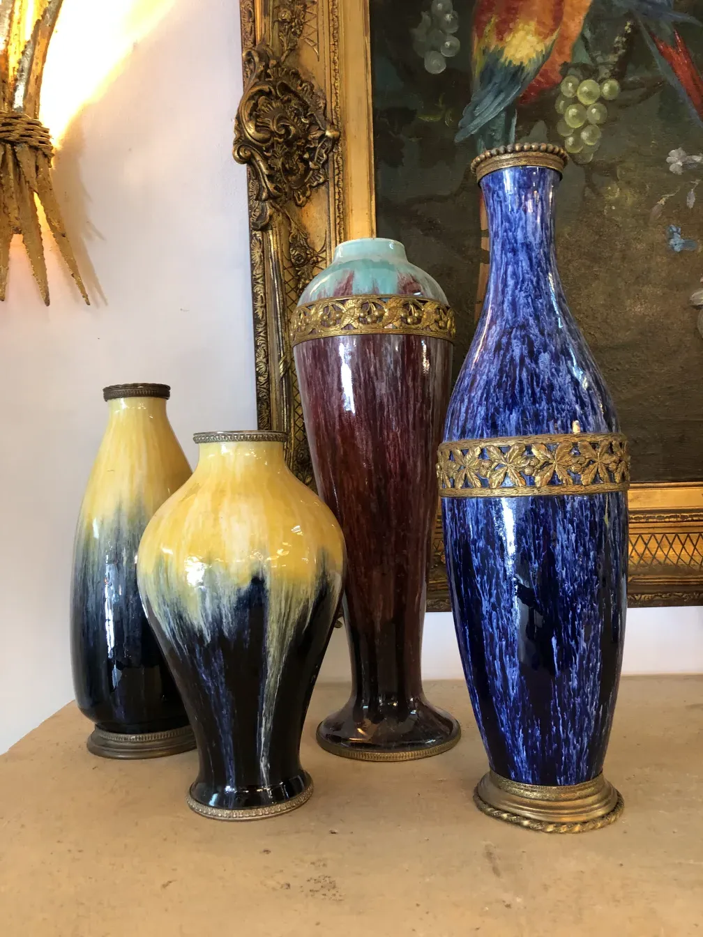 Conjunto de quatro vasos de cerâmica antiga Boch frères, com cores vibrantes como azul e amarelo, detalhes decorativos na base.