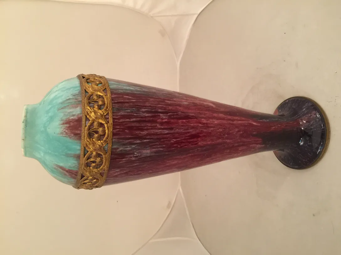 Vase en céramique ancienne avec un design bleu et rouge, accentué d'un bord doré.