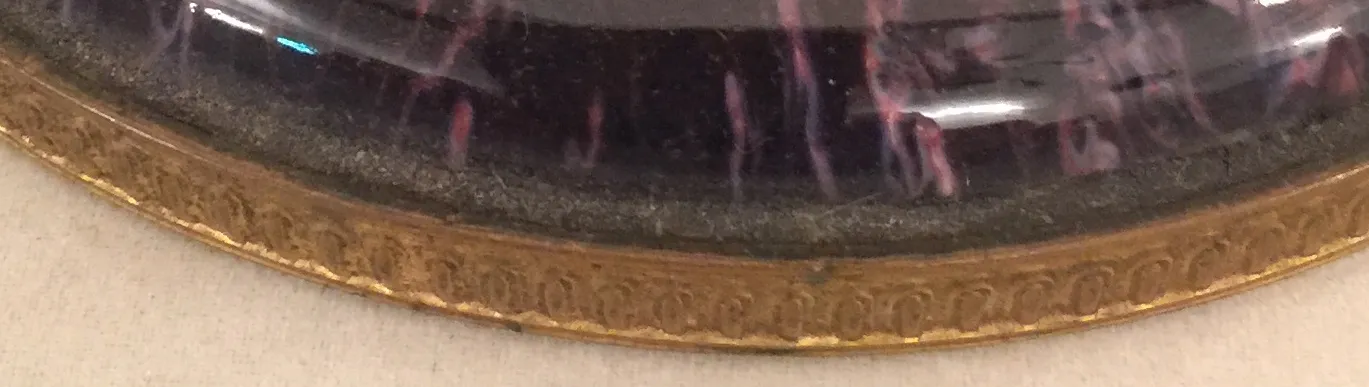 Ceramica antica con bordo decorativo dorato e toni scuri.