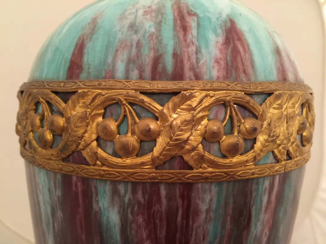 Antigua cerámica decorada en tonos turquesa y morado con borde dorado.