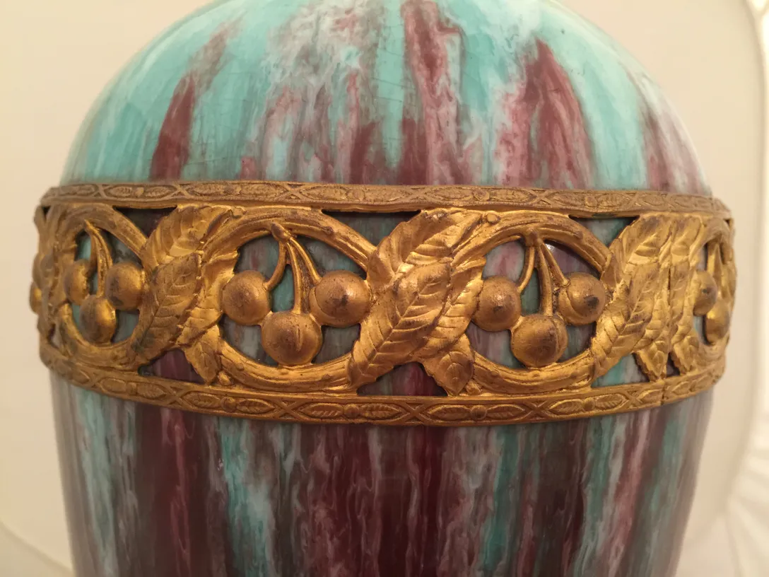 Céramique ancienne avec un design orné doré et des couleurs vibrantes dans un cadre classique.