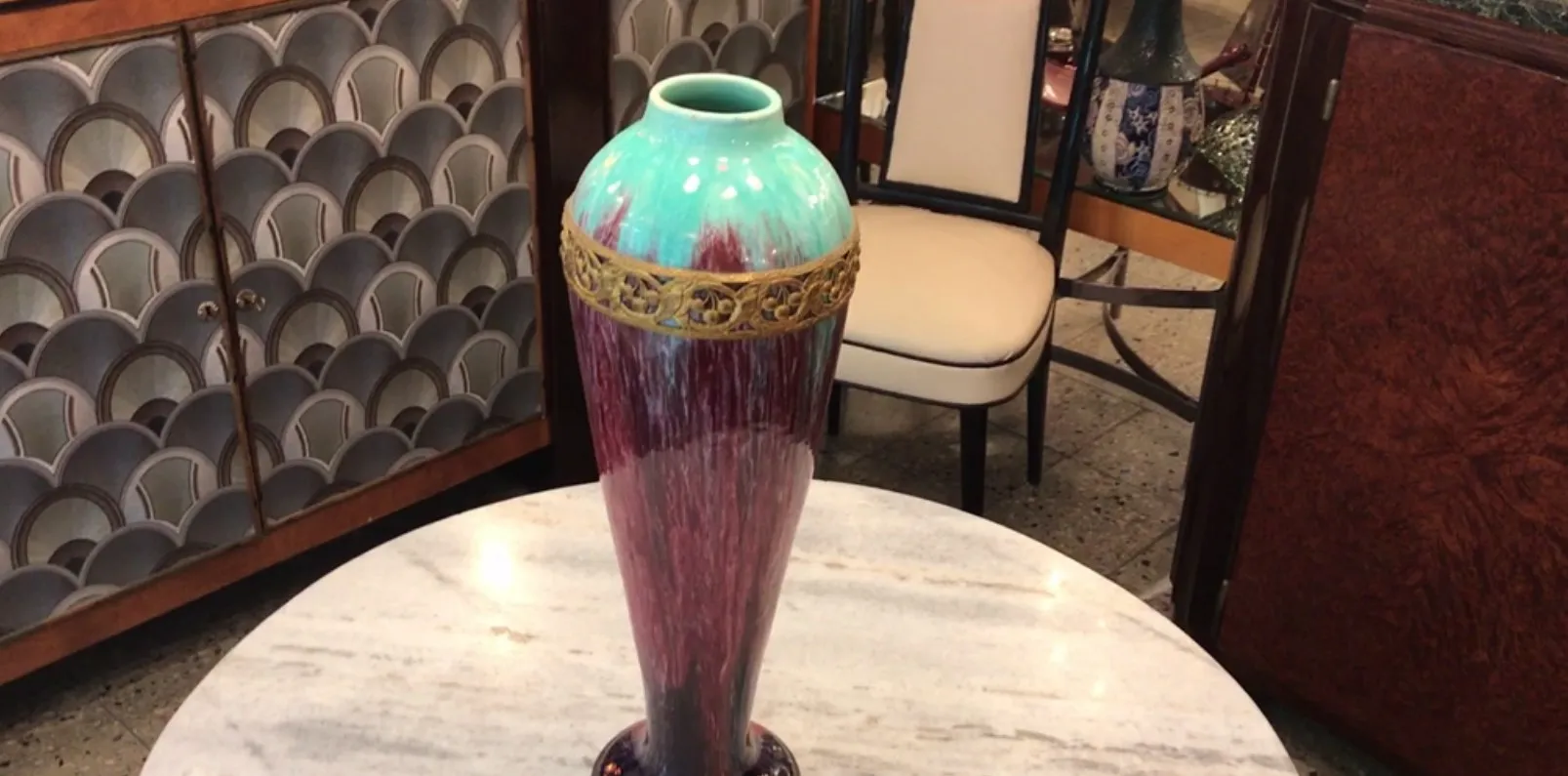 Antique ceramic Boch frères with decorative base and vibrant colors, set in an elegant environment.
