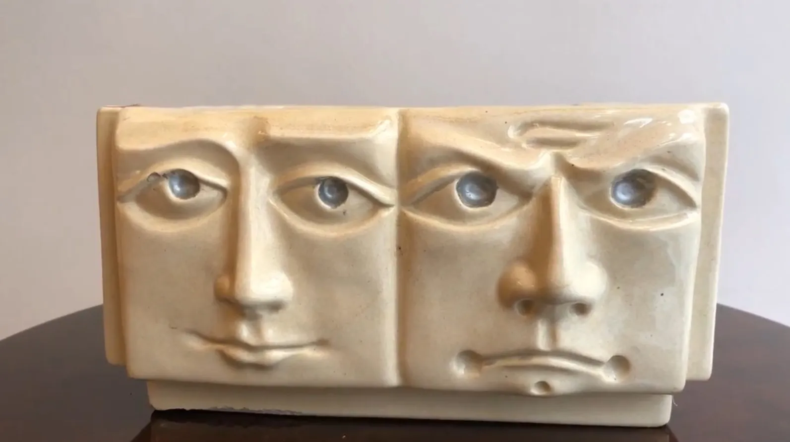 Ceramica antica con design di volti espressivi in beige