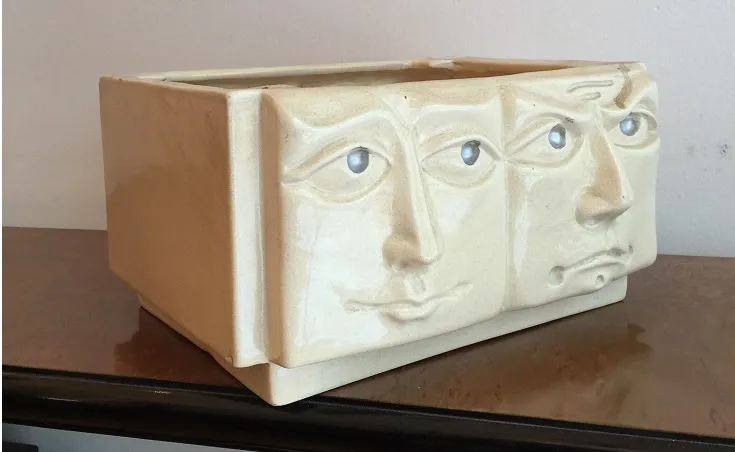 Cerâmica antiga com três faces esculpidas e detalhes azuis