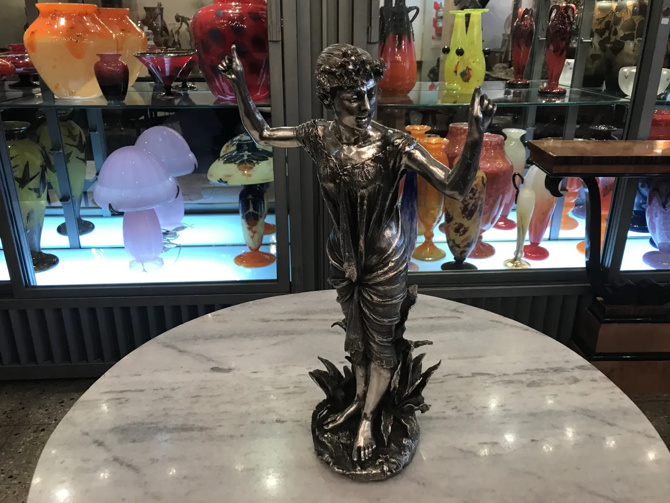 Sculpture antique d'une figure féminine dans un cadre élégant avec des vases colorés.