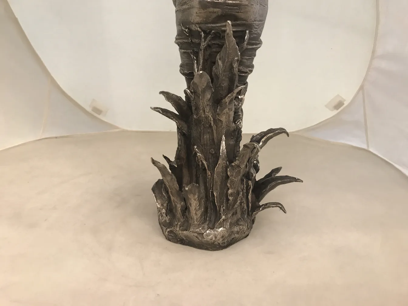 Ancient sculpture featuring leaf-like bases against a white background.