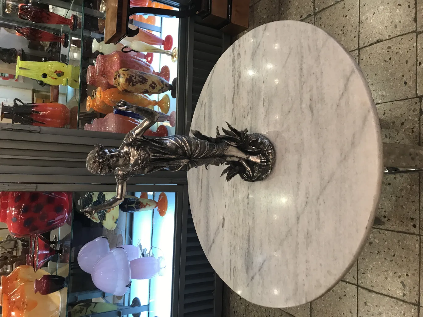 Antique sculpture of a figure on a marble table with colorful background.