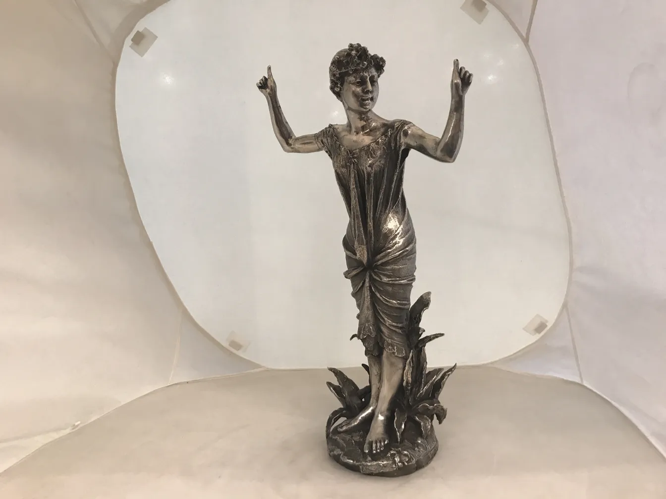 Sculpture ancienne d'une femme gesticulant parmi des plantes.