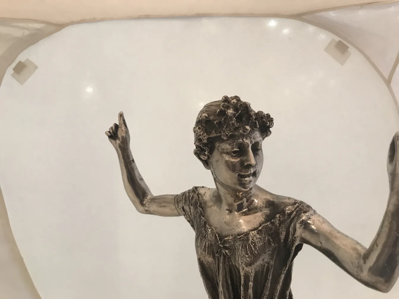 escultura antigua de mujer con corona floral, gesto elegante