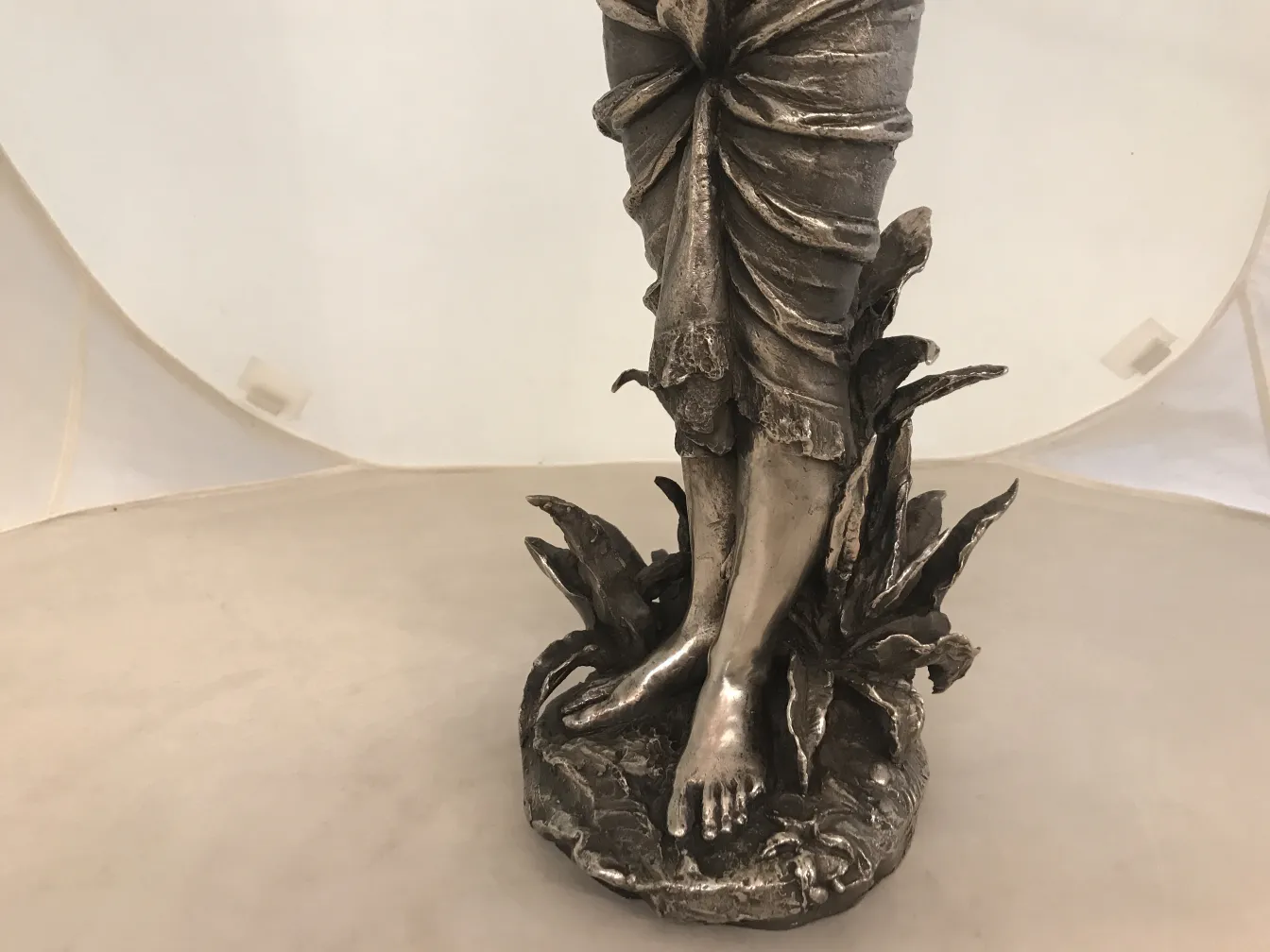 Alte Skulptur, die eine Figur in Bewegung auf einer dekorativen Basis darstellt