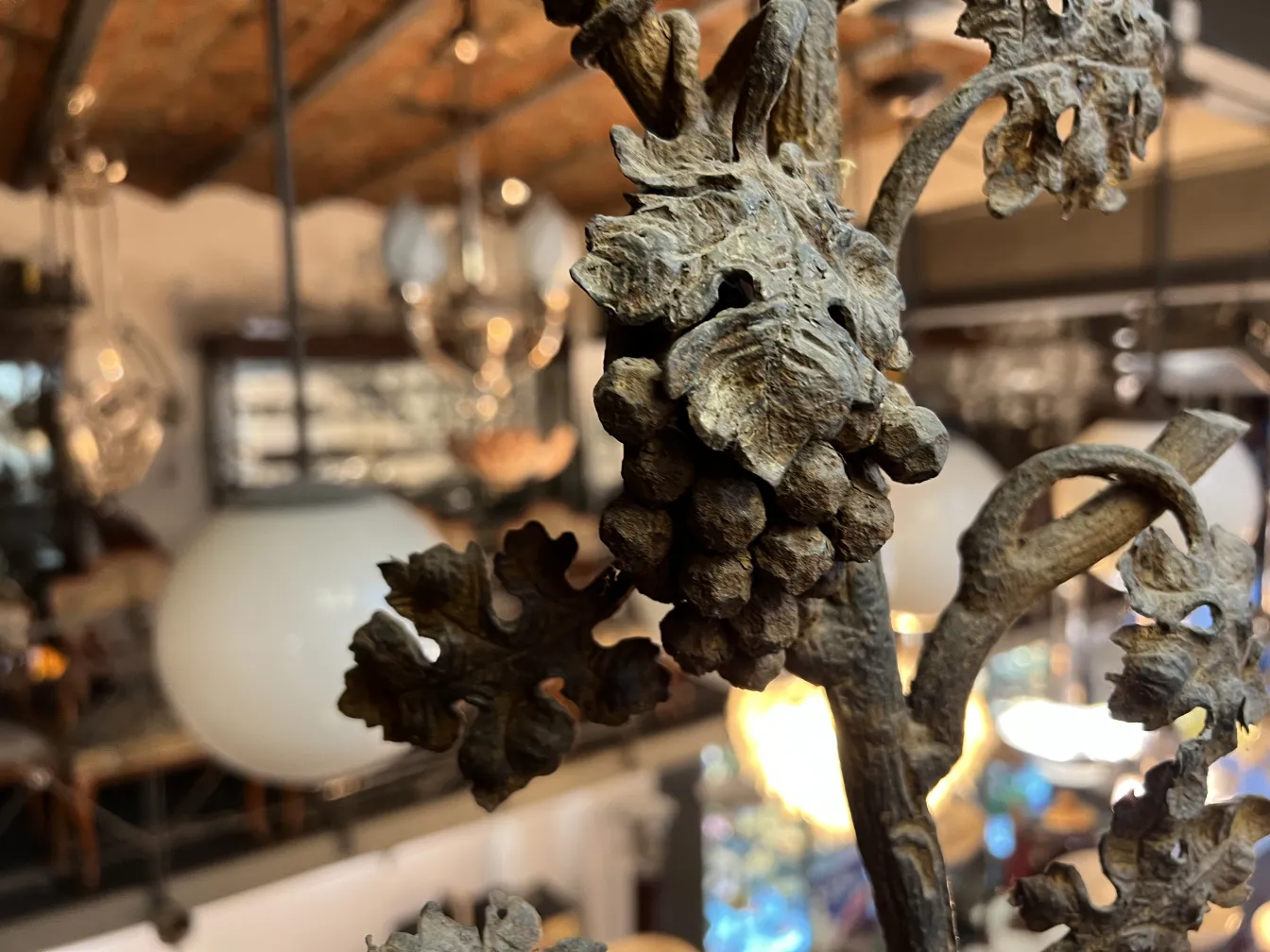 Close-up de uma escultura antiga de planta com detalhes de folhas e uvas, fundo de loja.