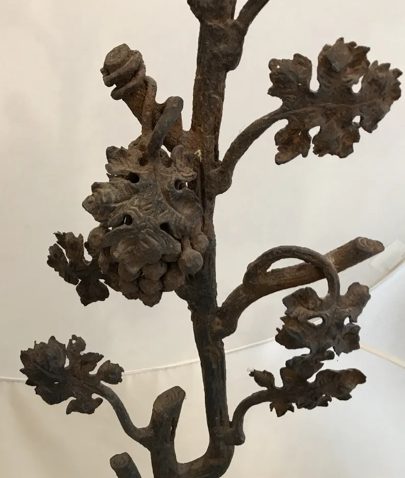 Escultura antigua que representa ramas y hojas en hierro, con detalles artísticos.