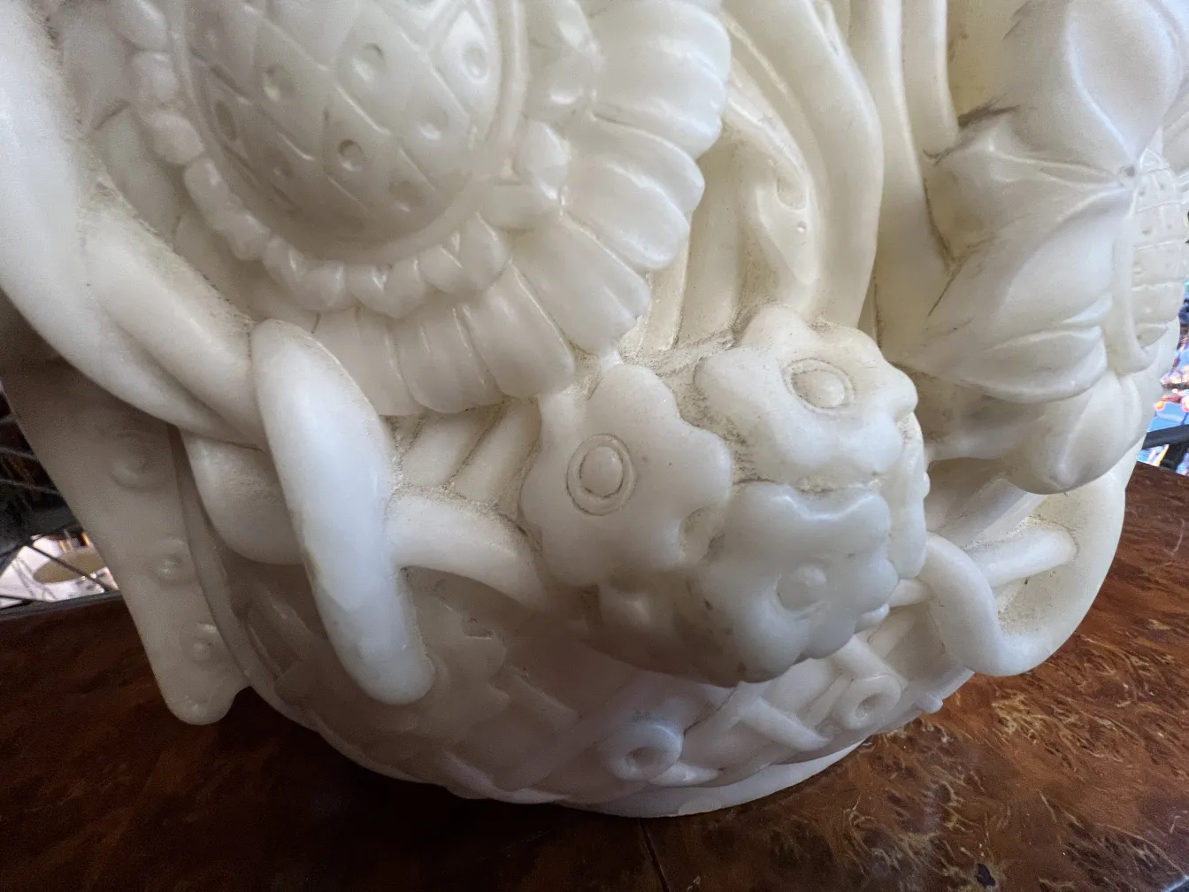 Antike Skulptur mit floralen Reliefdetails, eleganter Hintergrund.